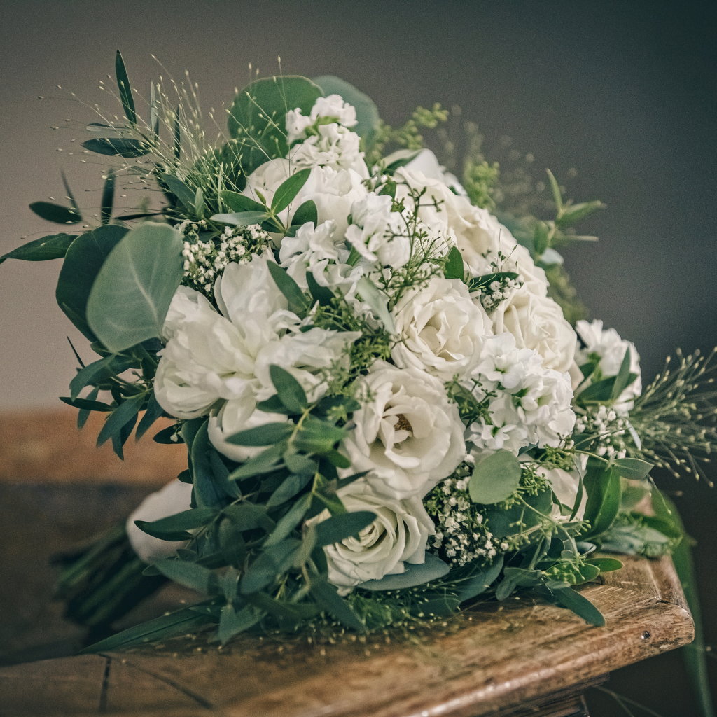 Hvid brudebuket med roser, grønne blade og gypsophila som smuk bryllupsdetalje på Sonnerupgaard Gods.