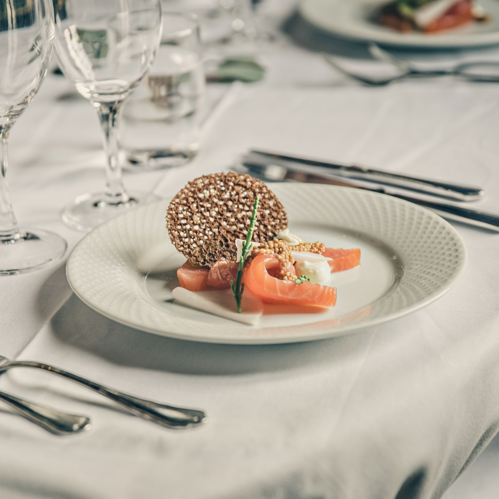 Elegant bryllupsmenu med laks, sprød garniture og opdækning med vinglas til festmiddag på Sonnerupgaard Gods.