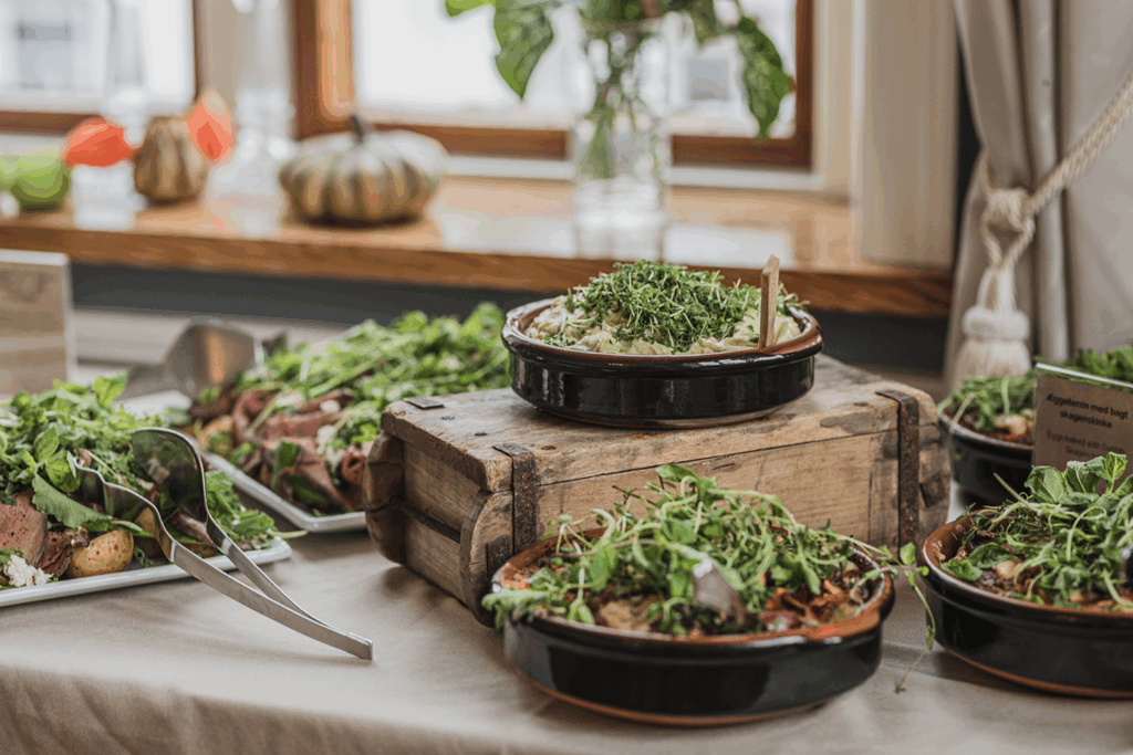 Indbydende buffet med friske salater og grønne retter i rustikke skåle – bæredygtig catering på Sonnerupgaard Gods