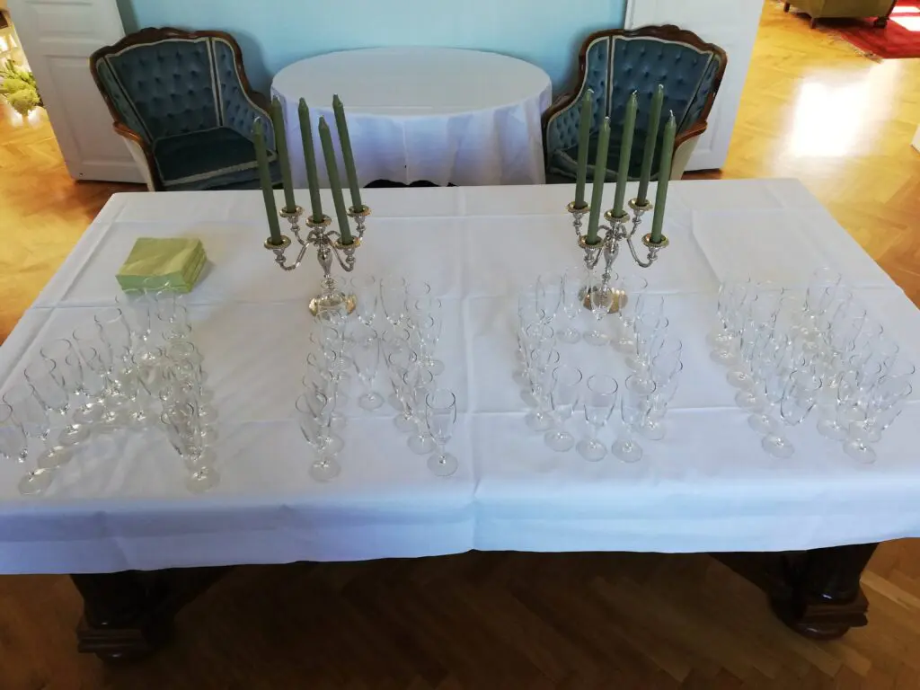 Champagneglas formet som navnet Aron på festbordet til en personlig barnedåb med grønne lys og elegante detaljer.