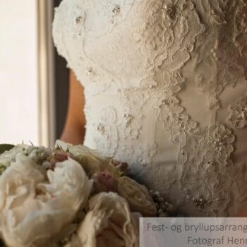Brudekjole med blonde- og perledetaljer samt brudebuket med hvide blomster