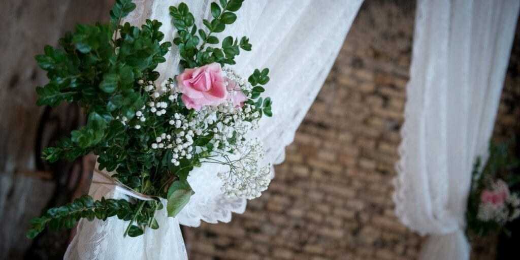 Blomsterbuket med grønne grene, lyserøde og hvide blomster bundet på vielsesportal