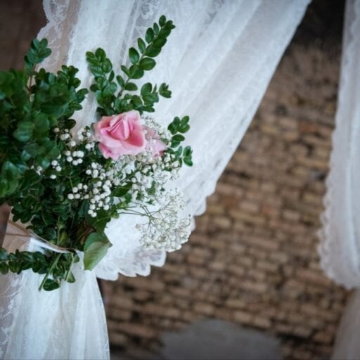 Blomsterbuket med grønne grene, lyserøde og hvide blomster bundet på vielsesportal