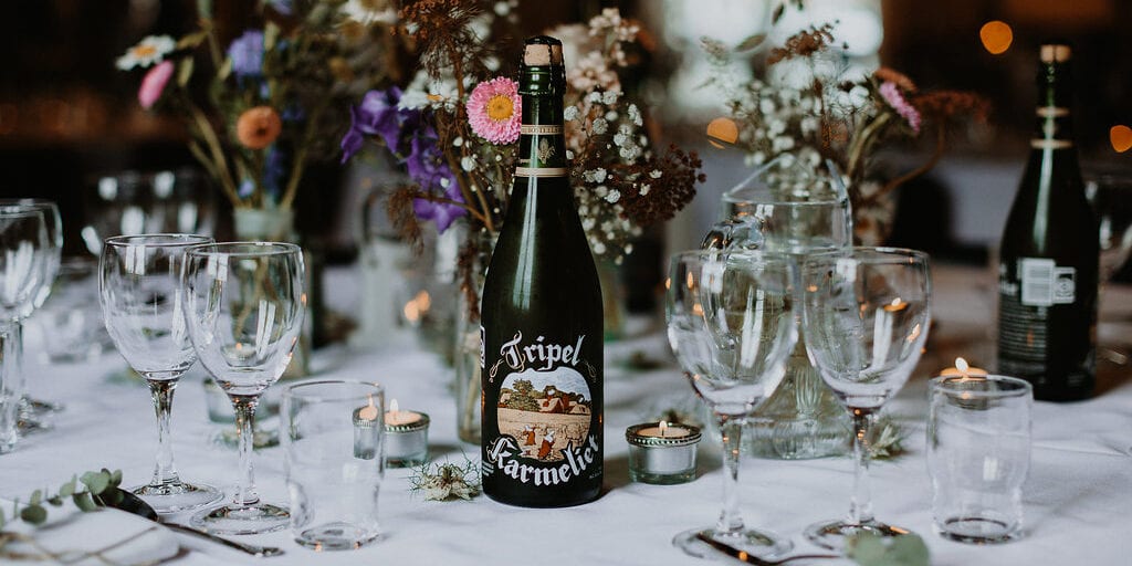 Centerpiece på bryllupsbord med grøftekantsblomster og rustikke øl