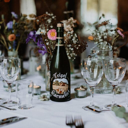 Centerpiece på bryllupsbord med grøftekantsblomster og rustikke øl