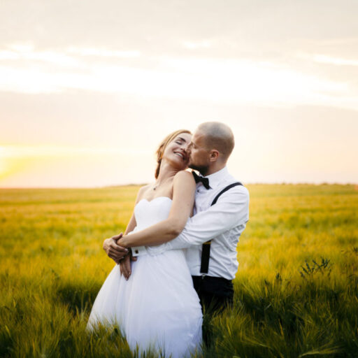 Bryllupsbillede af brudepar i mark med solnedgang