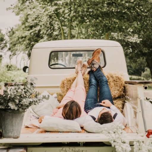 Brudepar slapper af på rustik truck med halmballer og blomster