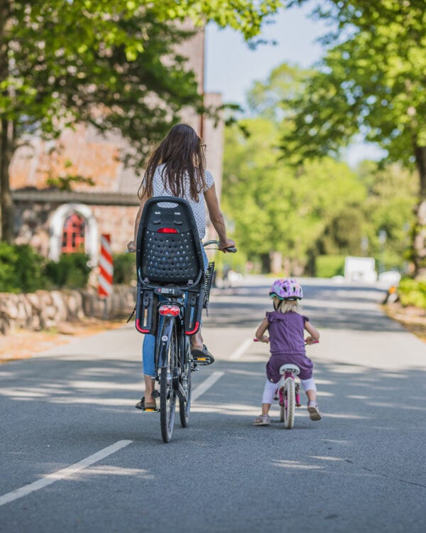 Mor og barn cykler i grønne omgivelser